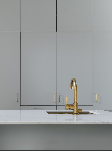 Harmaa keittiö kultaisella hanalla.